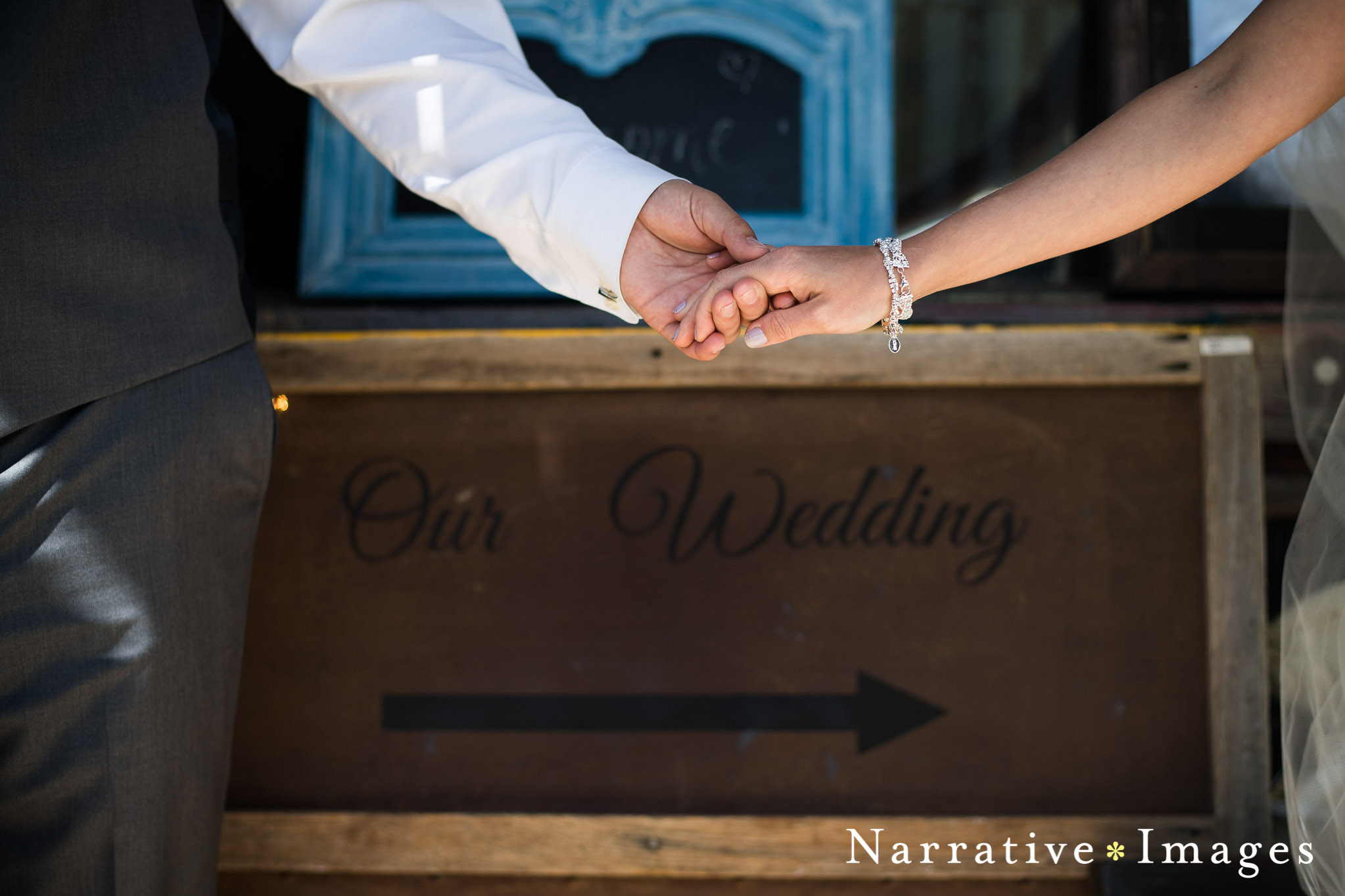 documentary wedding photo of wedding couples hands in front of antique wedding sign
