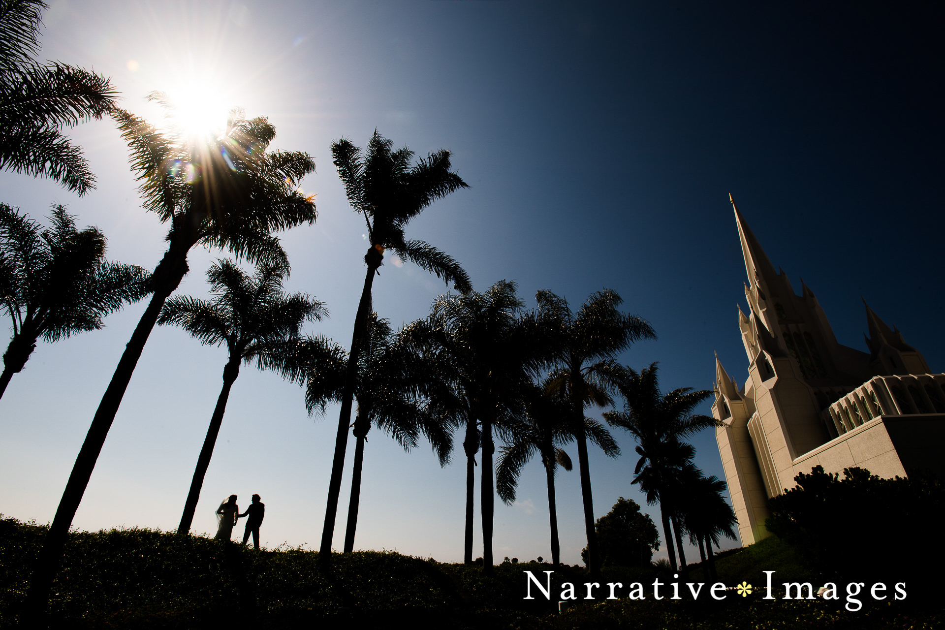 Bride and groom walk by palm trees at La Jolla Mormon Temple