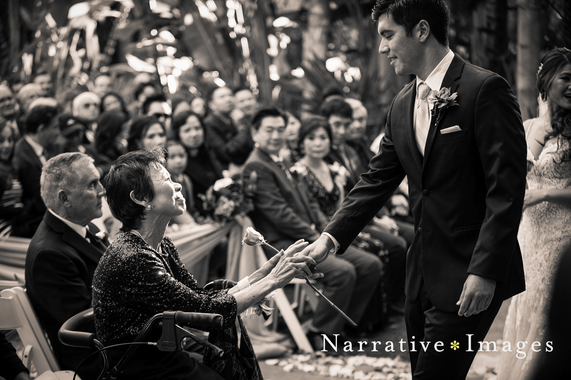 Groom gives his mother a rose during wedding ceremony at Grand Tradition Estate in Fallbrook