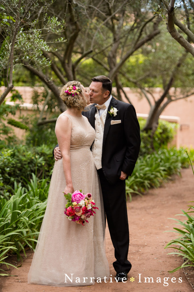 Married couple kisses amidst olive trees at Rancho Valencia Resort and Spa in Rancho Santa Fe