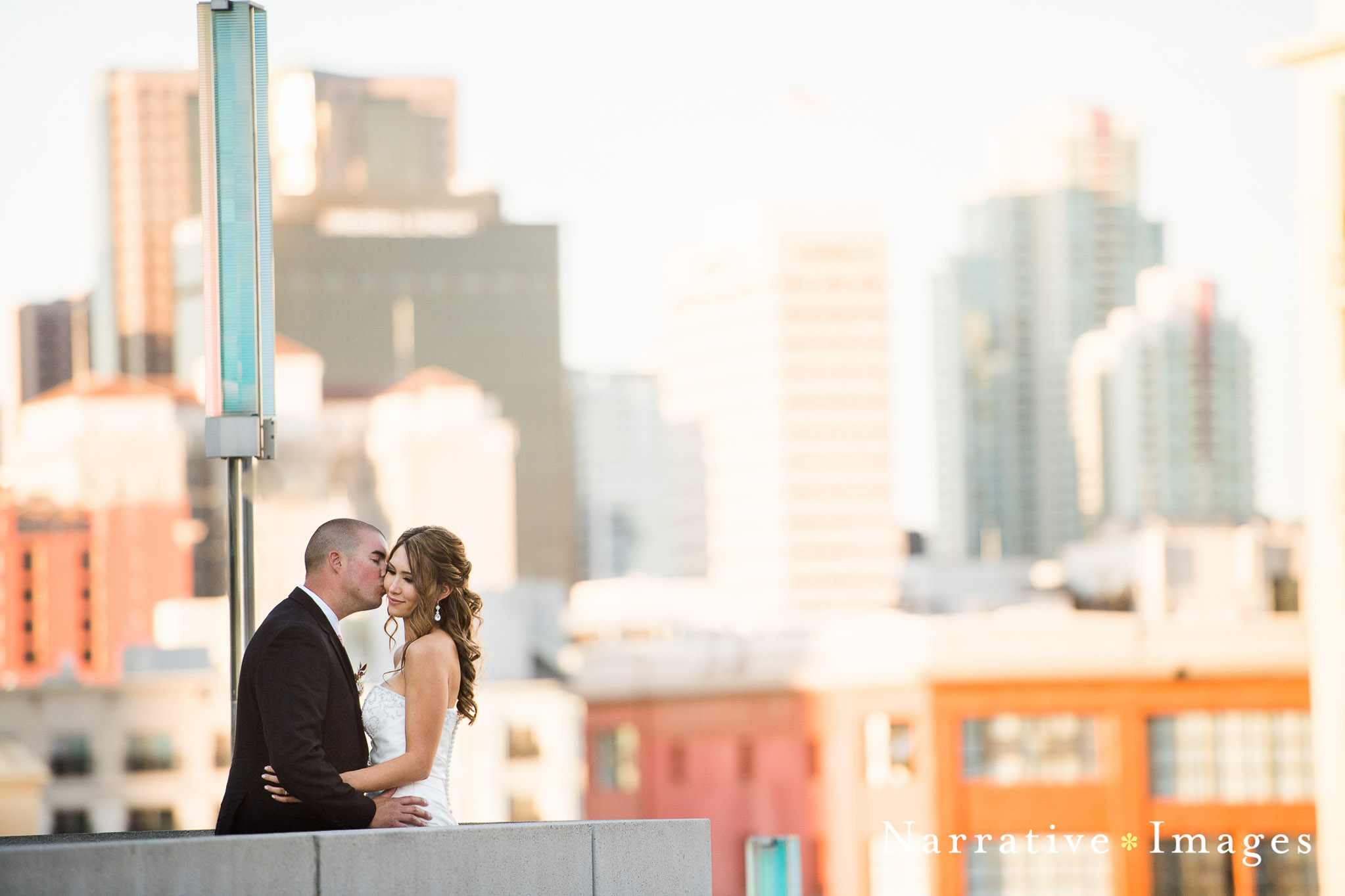 Married couple kissing with view of downtown san diego in background