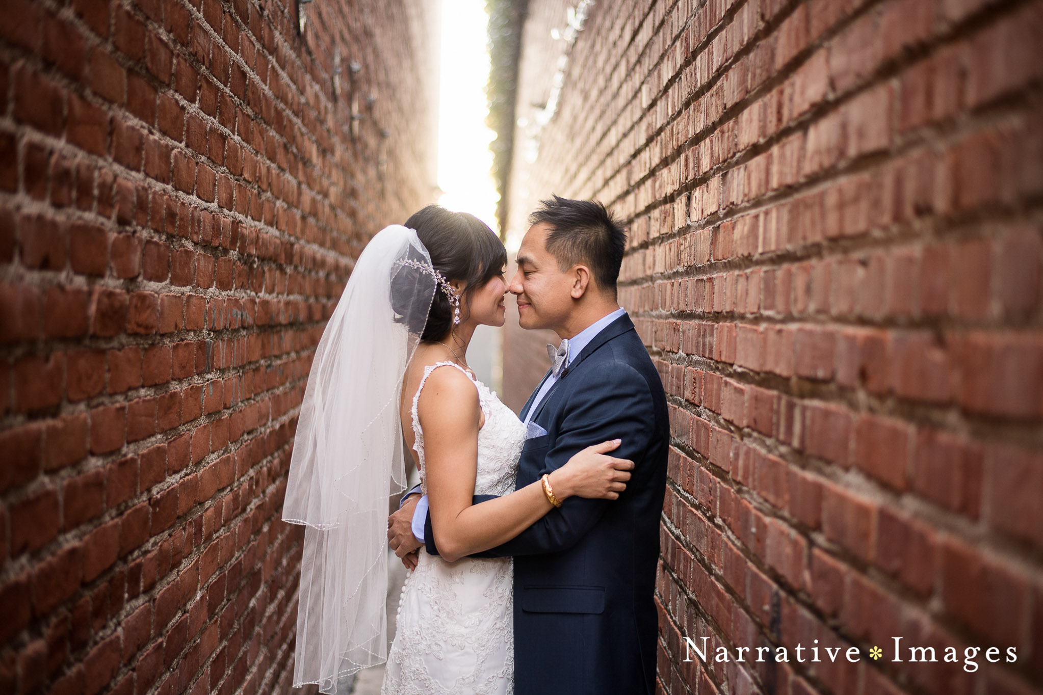 Bride and Groom in alleyway between brick walls looking into eachothers eyes