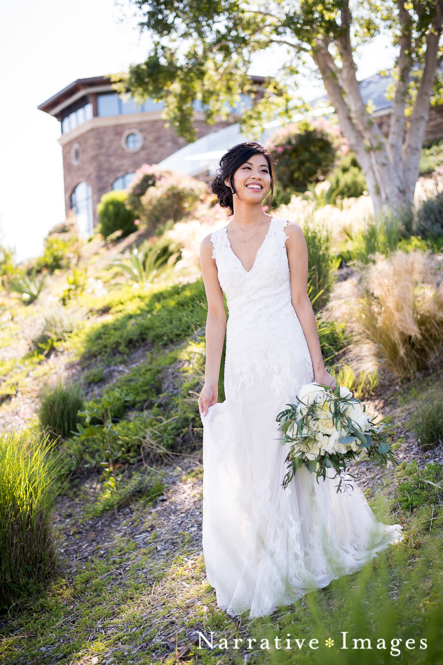 Bride in wedding dress holding natural bouquet and smiling at the crossings