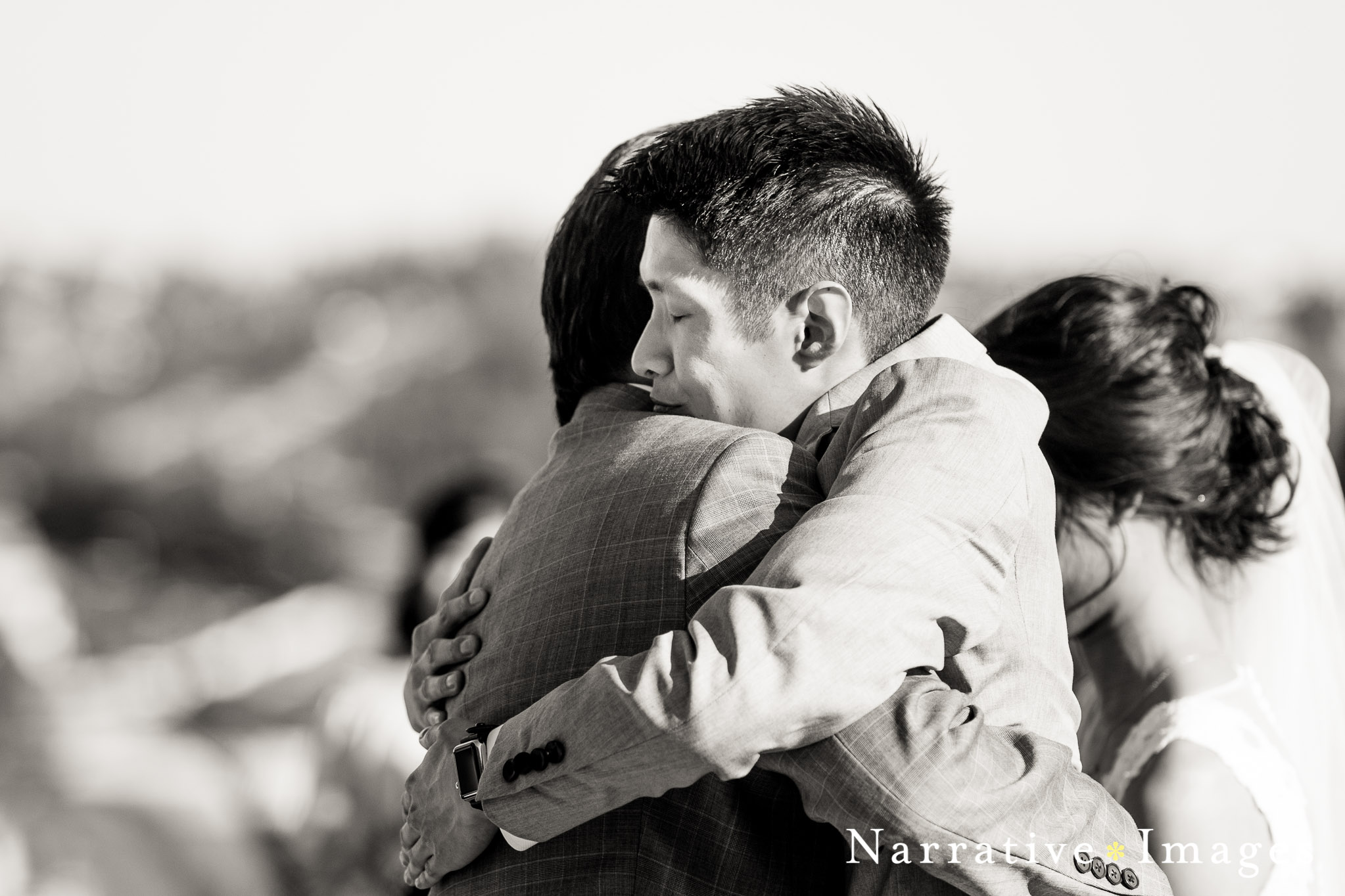 documentary wedding photography moment, groom hugs father at wedding in Carlsbad CA