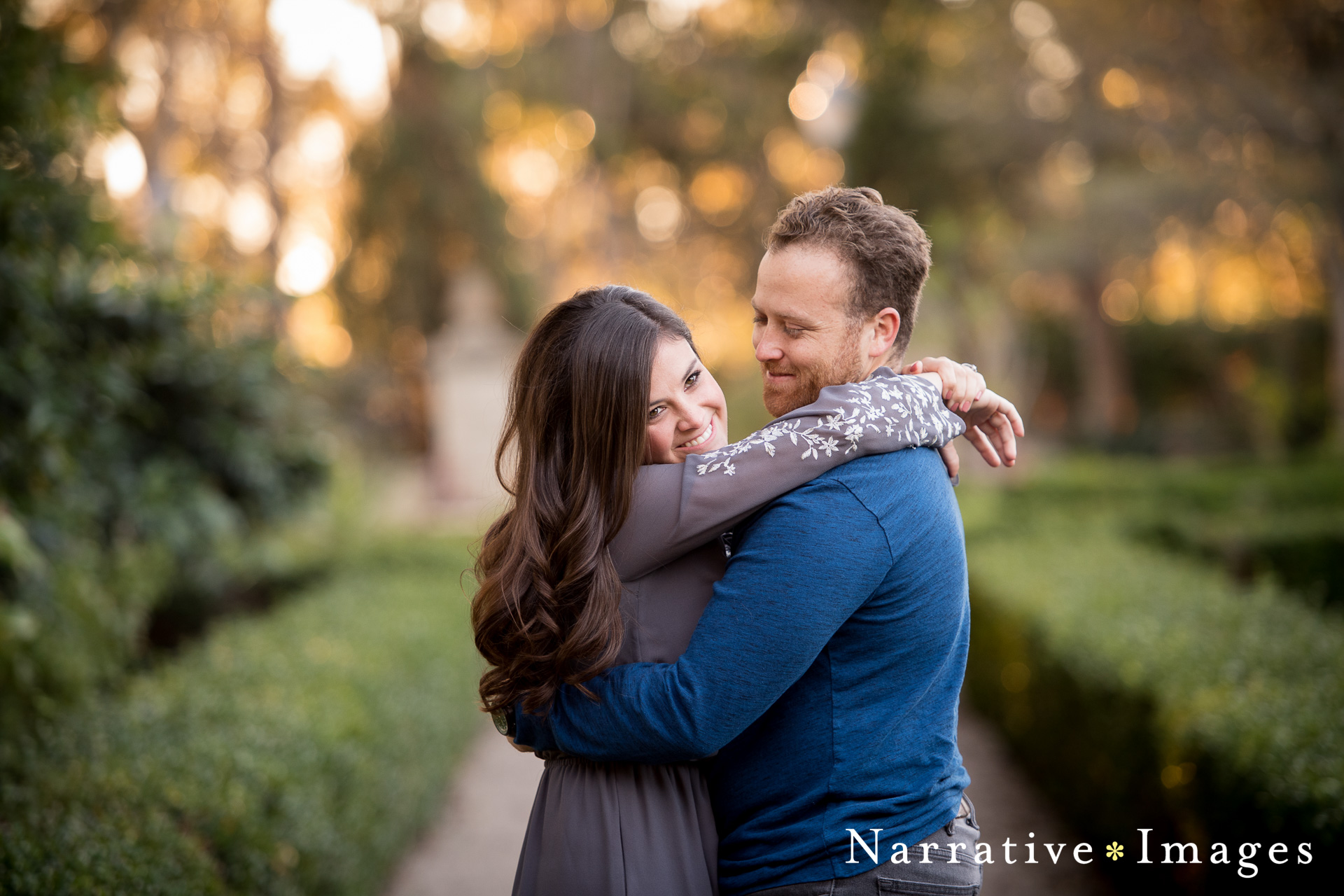 Couple hugs lovingly in Alcazar gardens in Balboa Park