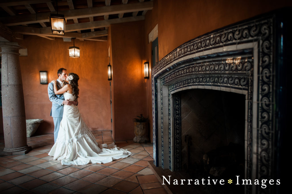 Bride and groom kiss near mosaic fireplace at Rancho Valencia Resort and Spa in Rancho Santa Fe