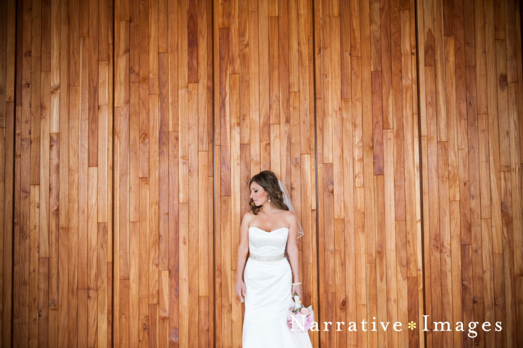 Bride poses against wooden wall at Scripps Seaside Forum in La Jolla, California