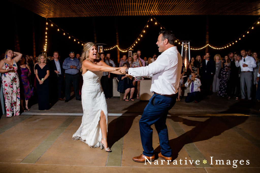 Bride and groom dance at their reception as guests watch at Scripps Seaside Forum in La Jolla, California