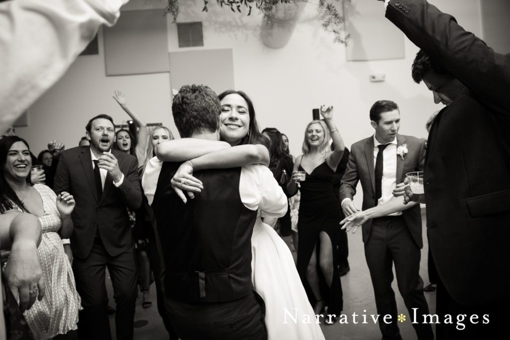 Bride smiles as she hugs her husband on the dance floor in black and white photo taken at The Lane wedding venue in San Diego